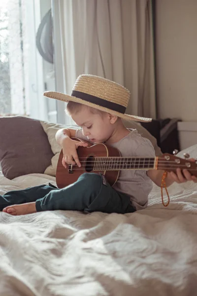 Evde gitar çalan, şapkalı küçük bir çocuk. Kırsal tarzda. Yaşam tarzı kavramı