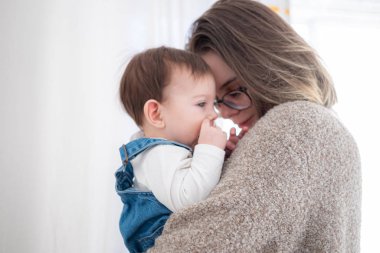 Anne küçük bebeği beyaz arka planda tutuyor. Yaşam tarzı aile kavramı. 