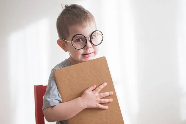 Kleine schattige peuter peuter peuter jongen met bril met boek kijken recht op camera. Terug naar schoolconcept — Stockfoto