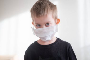 Beyaz arka planda tıbbi maskeli küçük çocuk portresi. Coronavirus koruma karantinası. Ev izolasyonu
