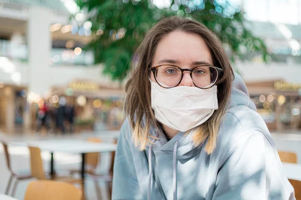 Mujer con mascarilla médica sentada en el centro comercial de cerca retrato. Protección contra la infección por virus Corona — Foto de Stock