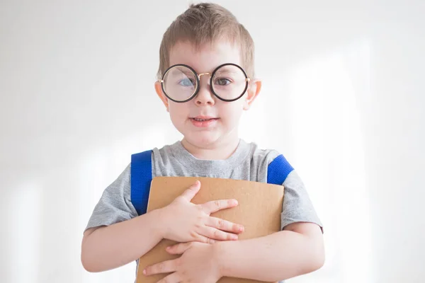 Kleine peuter met bril en rugzak en boek. Een kleuter met een bril. Terug naar schoolconcept — Stockfoto