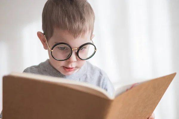 Bonito menino criança lendo um livro em óculos. Pré-escolar inteligente. Voltar ao conceito de escola — Fotografia de Stock