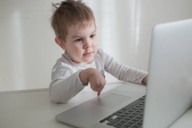Küçük çocuk çalışıyor, bilgisayardan bilgisayar öğreniyor. Uzaktan eğitim kavramı. Ev karantinası
