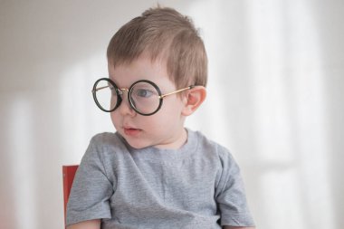 Gözlüklü, elinde kitapla kameraya bakan küçük tatlı anaokulu çocuğu. Okul konseptine dönelim.