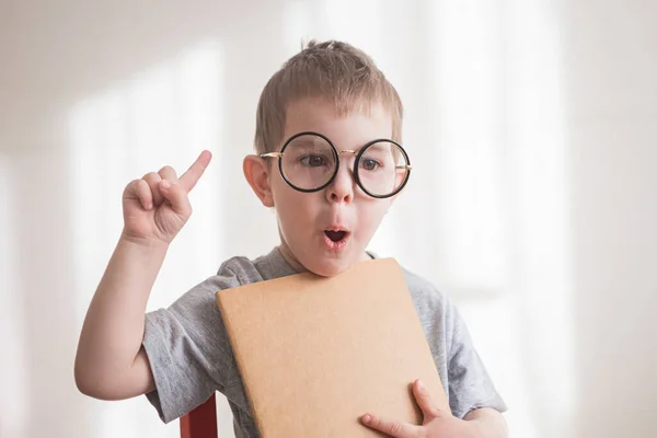 Gözlüklü, elinde fikir işareti olan küçük bir çocuk. Okul konseptine dönelim. — Stok fotoğraf
