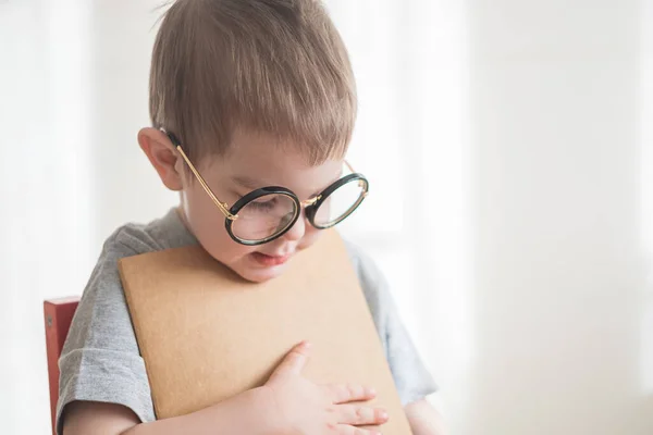 Petit garçon d'âge préscolaire mignon tout-petit dans des lunettes avec un livre regardant directement la caméra. Concept de retour à l'école — Photo