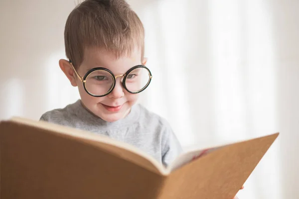 Aranyos kisfiú, szemüveges könyvet olvas. Okos óvodás. Vissza az iskolába — Stock Fotó