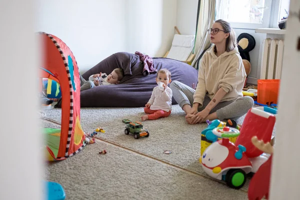 Mother making workout in messy nursery with kids around. Family lifestyle concept. Home workout social distancing self isolation — Stock Photo, Image