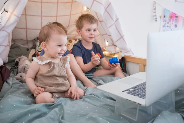 Drie kinderen die naar een laptop kijken, tekenfilms kijken, videochatten tijdens de quarantaine. door te brengen tijd thuis tijdens de afsluiting vanwege pandemie covid19 — Stockfoto