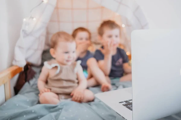 Трое детей смотрят на ноутбук, мультики, видео-чат во время карантина. время, проведенное дома во время изоляции из-за пандемии covid19 — стоковое фото