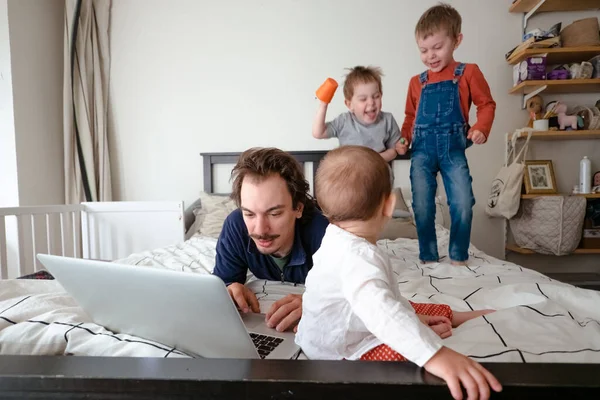 Man trying to work via laptop at home during quarantine with kids playing around. Family life during self isolation. Stay home. Work from home, home office — Stock Photo, Image