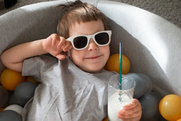 Peuter jongen in zonnebril zwemmen in bal zwembad thuis. Zelfisolatie quarantaine entertainment thuis. Vakantie toerisme in huis — Stockfoto