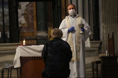 Roma, İtalya 9 Mayıs 2020: Maskeli bir rahip, Trastevere 'deki Santa Maria' da inançlı bir cemaate ayin ayini düzenledi. Covid-19 acil karantinasından sonra İtalya 'da ikinci aşamaya başlayan ilk hafta sonu..