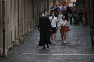 Roma, İtalya 9 Mayıs 2020: Maskeli bir rahip Roma sokaklarında yürüyor. Covid-19 acil karantinasından sonra İtalya 'da ikinci aşamaya başlayan ilk hafta sonu..
