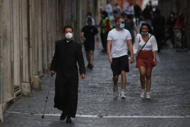 Roma, İtalya 9 Mayıs 2020: Maskeli bir rahip Roma sokaklarında yürüyor. Covid-19 acil karantinasından sonra İtalya 'da ikinci aşamaya başlayan ilk hafta sonu..