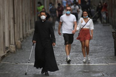 Roma, İtalya 9 Mayıs 2020: Maskeli bir rahip Roma sokaklarında yürüyor. Covid-19 acil karantinasından sonra İtalya 'da ikinci aşamaya başlayan ilk hafta sonu..