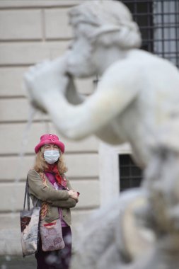 Roma, İtalya 9 Mayıs 2020: Pembe şapkalı ve maskeli kadın, Roma 'daki Piazza Navona' daki Bernini çeşmesine bakıyor. Covid-19 acil karantinasından sonra İtalya 'da ikinci aşamaya başlayan ilk hafta sonu..