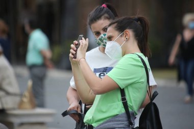 Roma, İtalya 9 Mayıs 2020: Maskeli kızlar Roma 'daki Piazza Venezia' da fotoğraf çekiyor. Covid-19 acil karantinasından sonra İtalya 'da ikinci aşamaya başlayan ilk hafta sonu..
