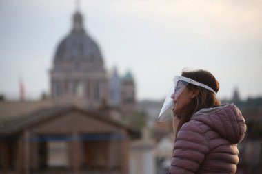 Roma, İtalya 9 Mayıs 2020: Koruyucu yüz maskeli kadın Roma 'nın manzarasına bakıyor. Covid-19 acil karantinasından sonra İtalya 'da ikinci aşamaya başlayan ilk hafta sonu..