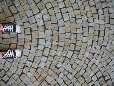 Arnavut kaldırımlı doku ve spor ayakkabı ayakkabılar. Şehir yolun Üstten Görünüm