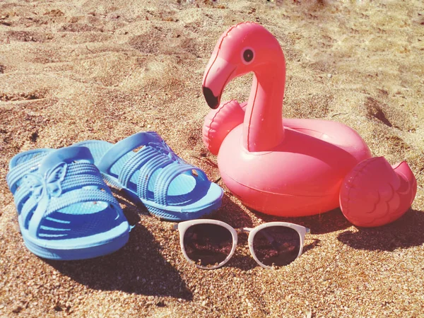 Sommer-Strandszene mit Flamingo, Flip-Flops und Sonnenbrille im Sand und warmem Sonnenlicht — Stockfoto