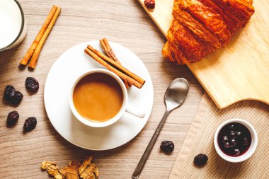 Kahvaltınız, kahveniz ve kruvasanlarınızla ahşap masada.