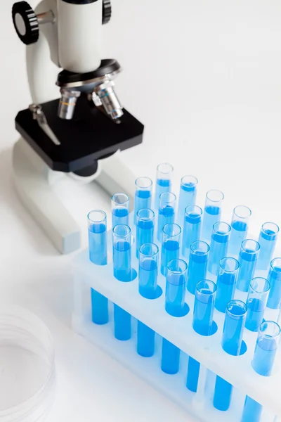 Tubes with liquid and microscope on white background — ストック写真