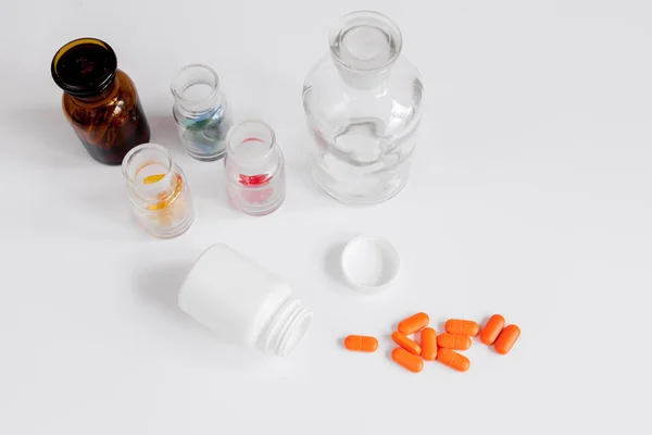Χρωματιστά χάπια σε γυάλινα μπουκάλια σε λευκό φόντο — Φωτογραφία Αρχείου