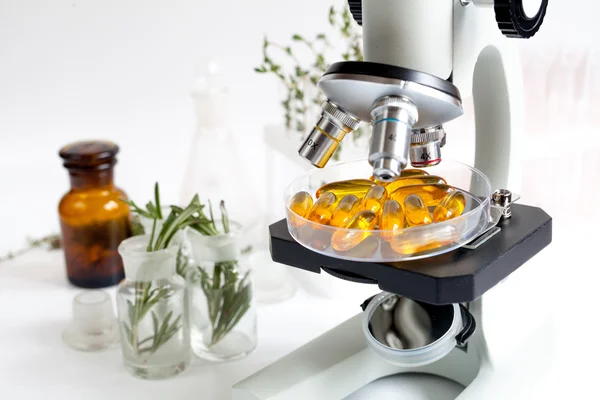 Concept - vérifier les compléments alimentaires en laboratoire au microscope — Photo