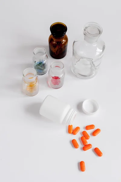 Pillole colorate in bottiglie di vetro su sfondo bianco — Foto Stock