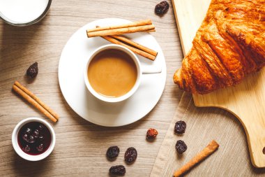 Kahvaltınız, kahveniz ve kruvasanlarınızla ahşap masada.