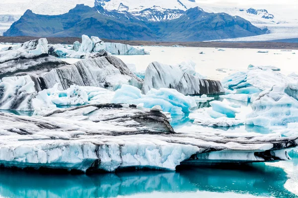 İzlanda, bulutlu hava, Ufuktaki dağların buzul gölünde. Buzul Gölü gökyüzü yansıtır