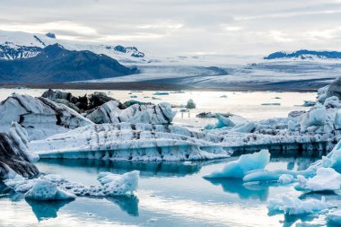 İzlanda, bulutlu hava, Ufuktaki dağların buzul gölünde. Buzul Gölü gökyüzü yansıtır