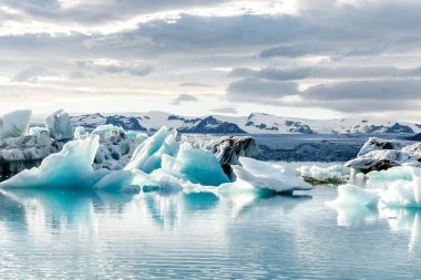 İzlanda, bulutlu hava, Ufuktaki dağların buzul gölünde. Buzul Gölü gökyüzü yansıtır