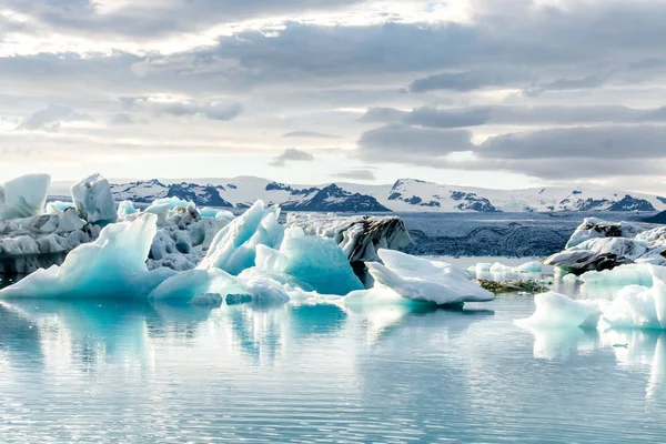 İzlanda, bulutlu hava, Ufuktaki dağların buzul gölünde. Buzul Gölü gökyüzü yansıtır
