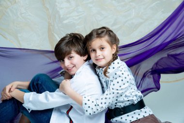 Stüdyoda gri arka planda poz veren tatlı çocuklar.