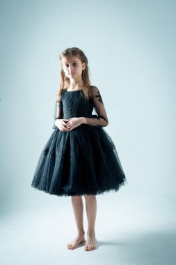 Siyah elbiseli örnek kız fotoğraf stüdyosunun gri arka planında. 