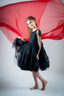 Gri arka planda fotoğraf stüdyosunda poz veren muhteşem siyah elbiseli güzel bir kız. 