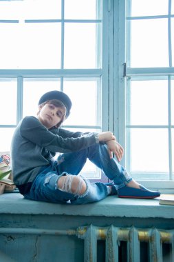 Siyah bereli yakışıklı çocuk pencere kenarında oturuyor. 