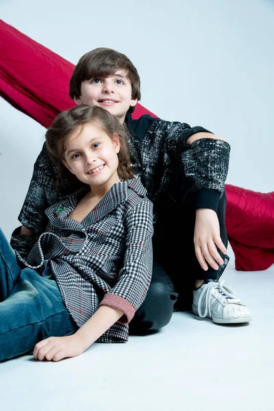Niedliche Kinder Sitzen Studio Auf Grauem Hintergrund Mit Roter Leinwand — Stockfoto