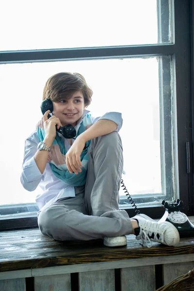 창가에 앉아서 전화로 얘기하는 귀여운 — 스톡 사진