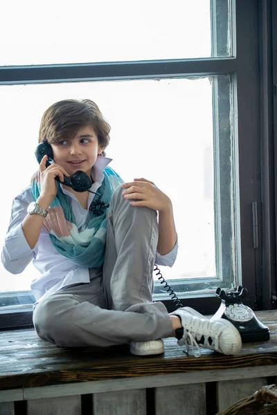 창가에 앉아서 전화로 얘기하는 귀여운 — 스톡 사진