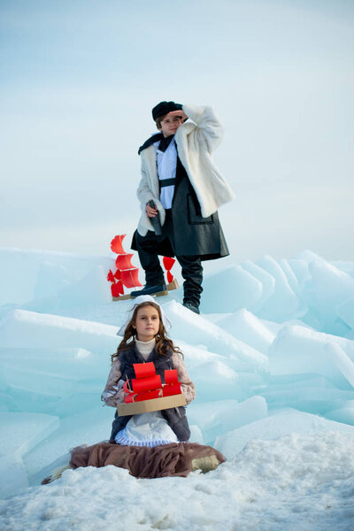 children playing on iceberg with wooden ship toys on winter background