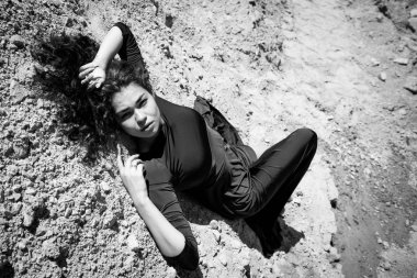 Şefkatli ve güzel bir kadın büyük beyaz bir kum ocağında yatıyor.