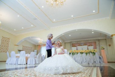 Gelinlik giymiş güzel bir sarışın ve makyaj sanatçısı. 