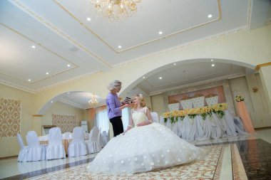 Gelinlik giymiş güzel bir sarışın ve makyaj sanatçısı. 