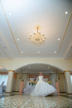 Gelinlik giymiş, mavi gözlü ve dudaklarında kırmızı ruj olan güzel sarışın kız.