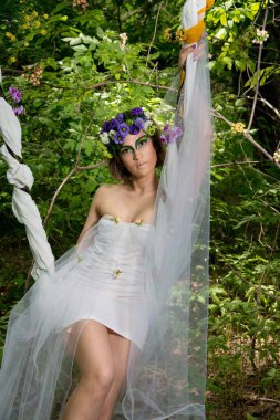 Ormanda poz veren bir çiçek çelengi içinde güzel bir gelin.