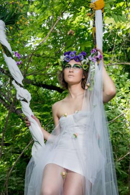 Ormanda poz veren bir çiçek çelengi içinde güzel bir gelin.